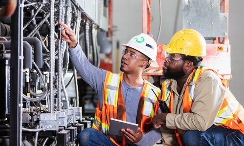 Two servicemembers in hard hats and safety vests review technical equipment at a Florida job site, representing hands-on SkillBridge internship experience with civilian employers.