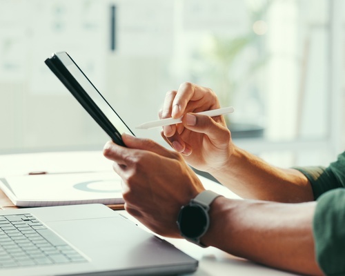Two people collaborate over a laptop and notebook, representing Veterans Florida's Modeling Cohort business validation training for veteran entrepreneurs in Florida.